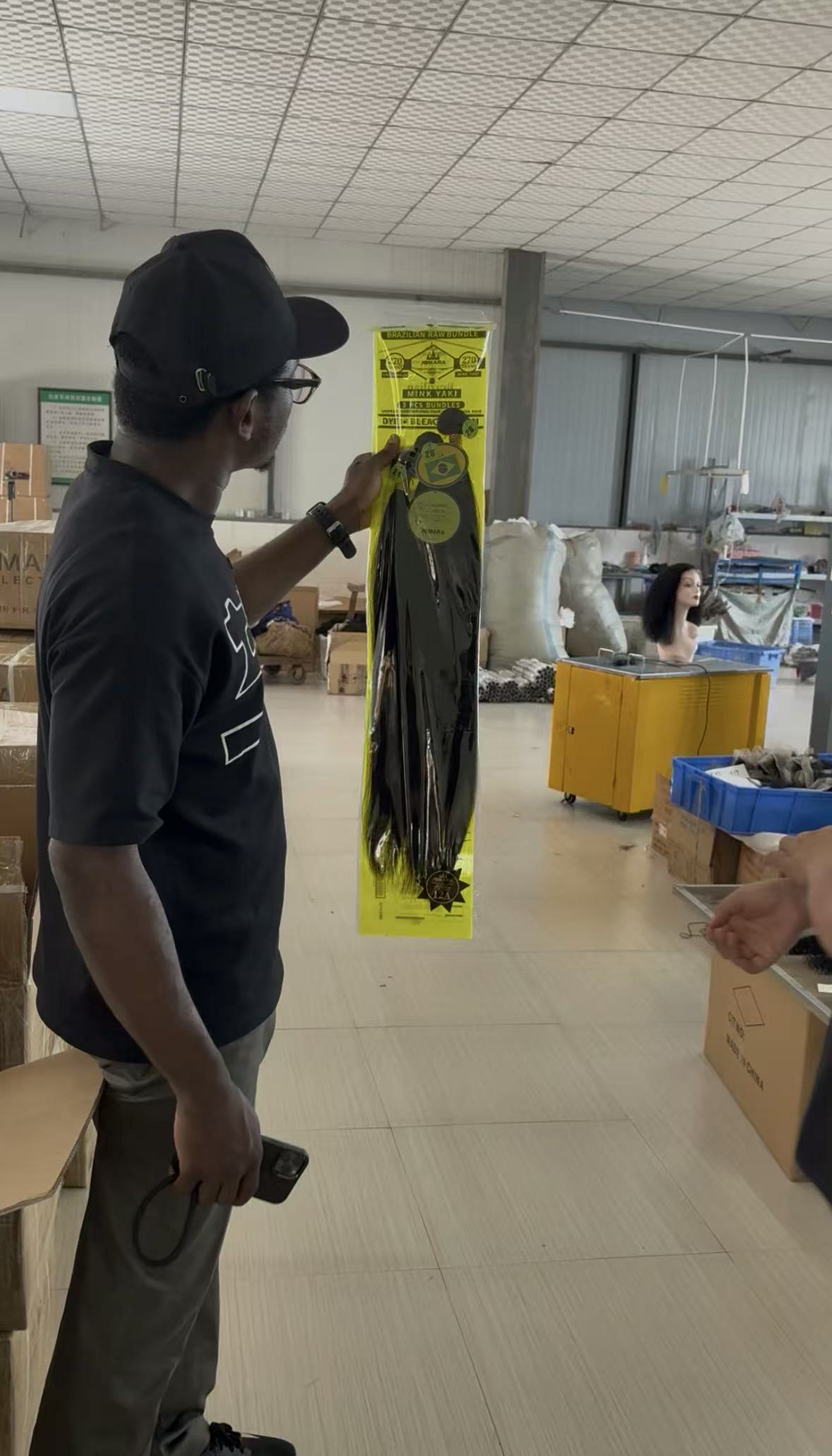 Customer inspecting a packaged Brazilian raw hair bundle inside the factory