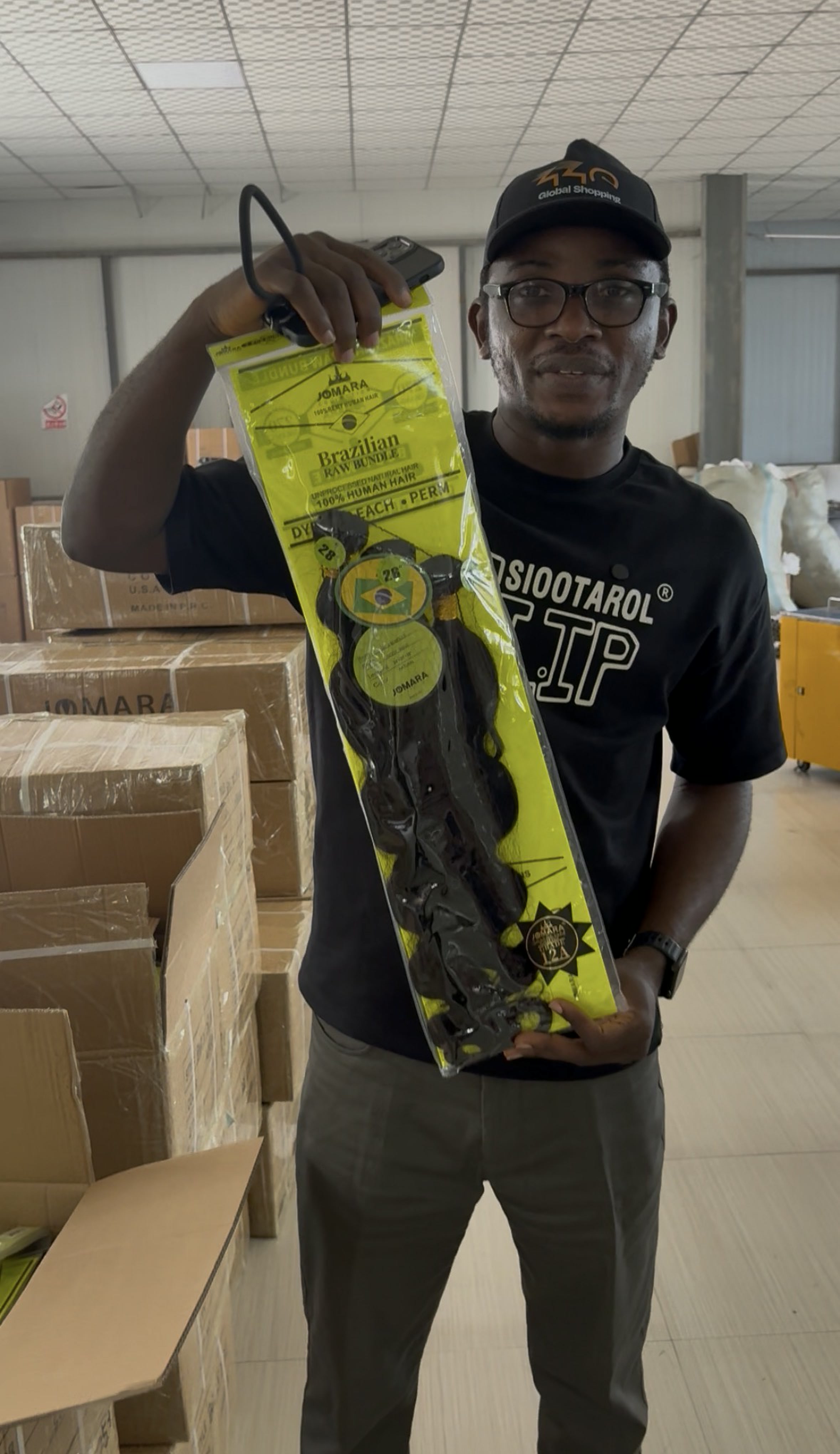 Customer holding a packaged Brazilian raw hair bundle in the factory