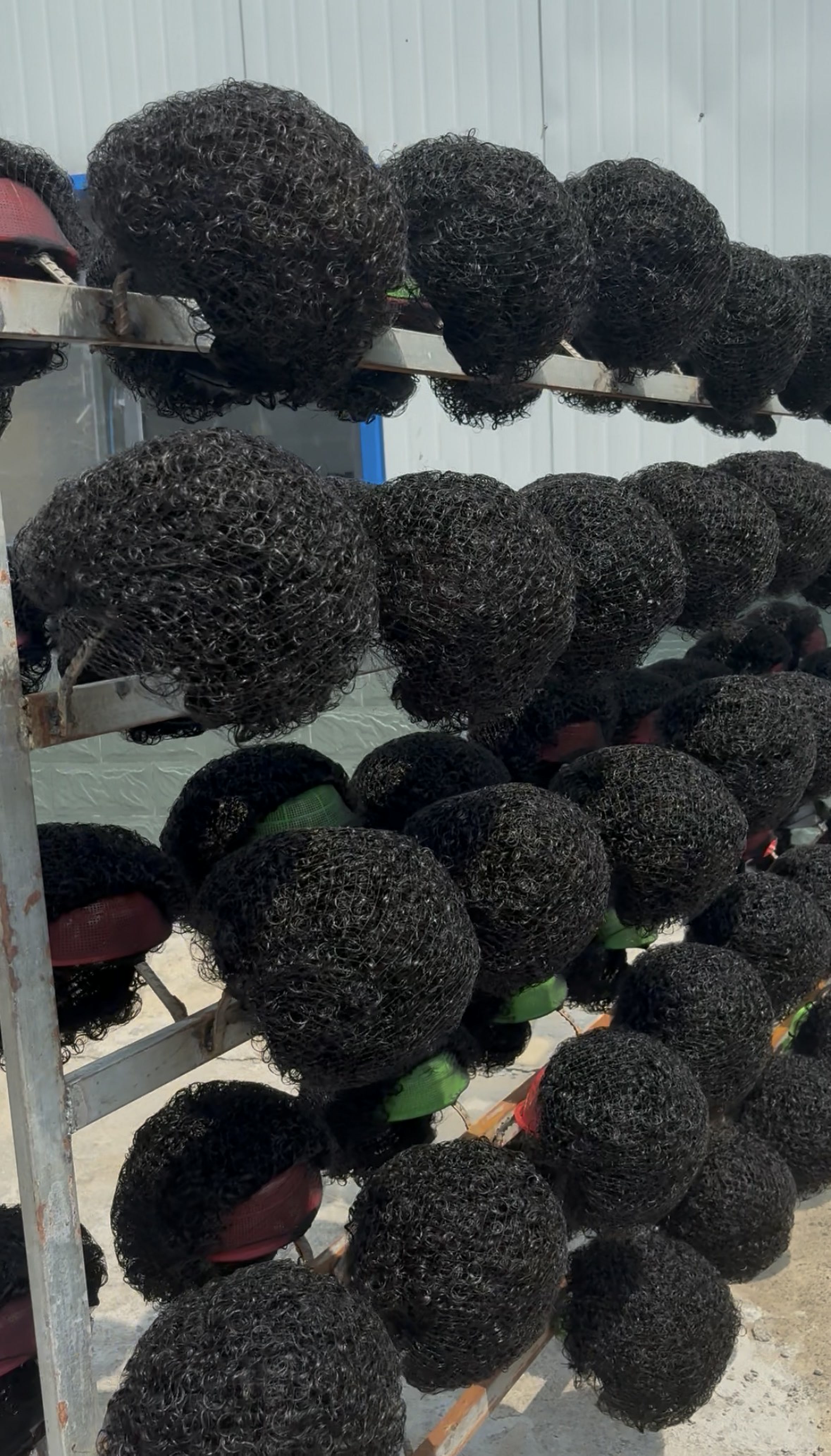 Rows of finished curly wigs arranged on factory storage racks